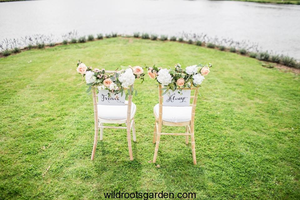 two decorative chairs on grass field near body of water,Trees For Wedding Ceremony