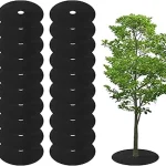 The image shows a close-up of a weed control mulch mat laid around a young tree trunk.